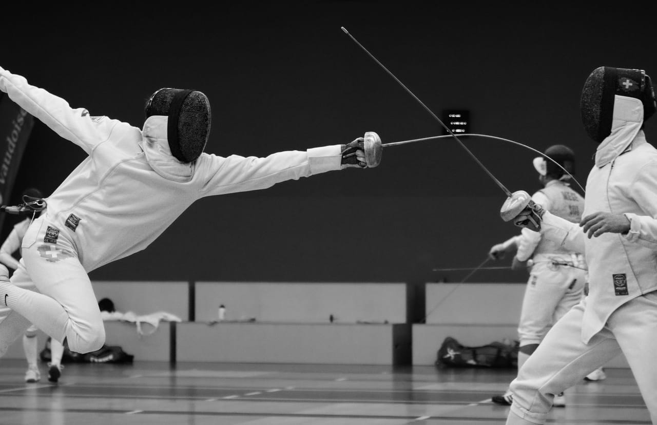 Group of fencers on a court with fencing equipment