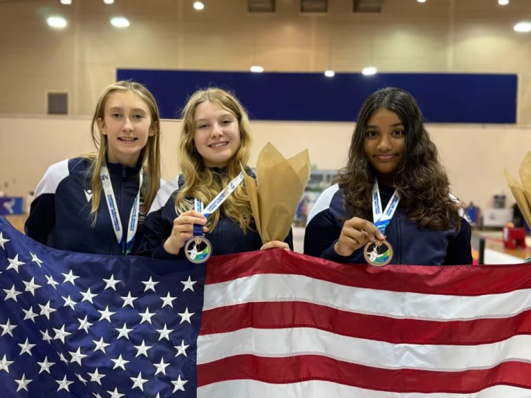 Maddie Burks and teammates showing their Pan American medals with a U.S. flag